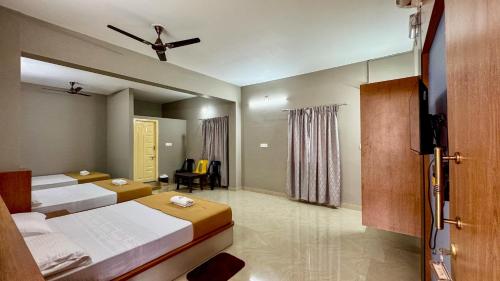 a bedroom with two beds and a flat screen tv at Ratna Residency in Udupi