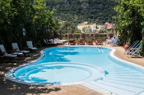 a swimming pool with chairs and a woman sitting in a chair next to it at Residence Villaggio Verde in Sorrento