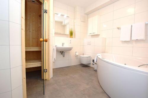 a bathroom with a tub and a toilet and a sink at Apartmenthaus Scharmützelsee inkl Nebenkosten in Wendisch Rietz