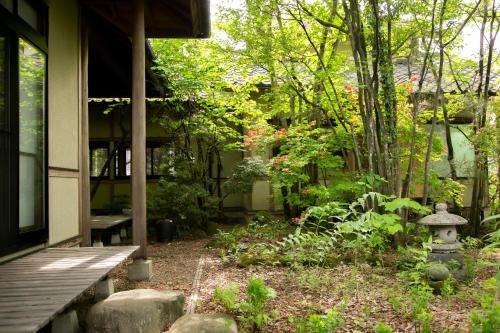 a garden in front of a house with a bird bath at 里山でのんびり遊べる宿-風音翆舎 Kanon suisha in Kawaba