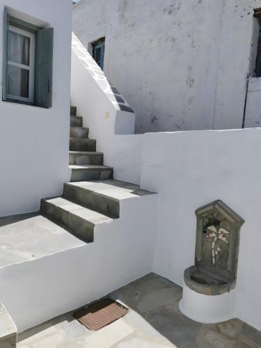 a staircase in a white building with a clock at Amorgos Meltemi Apartments in Amorgos