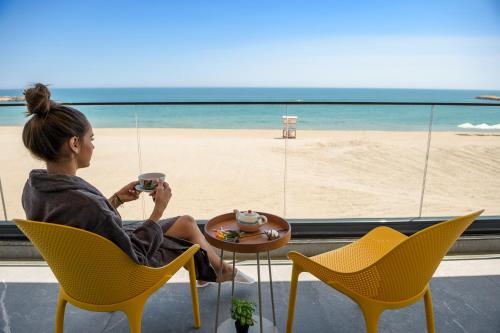 a woman sitting at a table looking out at the beach at Mirage Beach Spa Hotel in Eforie Nord