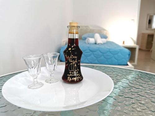 a bottle of wine on a plate with two glasses at Amorgos Meltemi Apartments in Amorgos