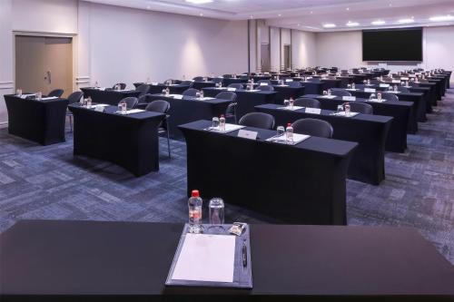 a conference room with tables and chairs and a screen at Southern Sun Newlands in Cape Town