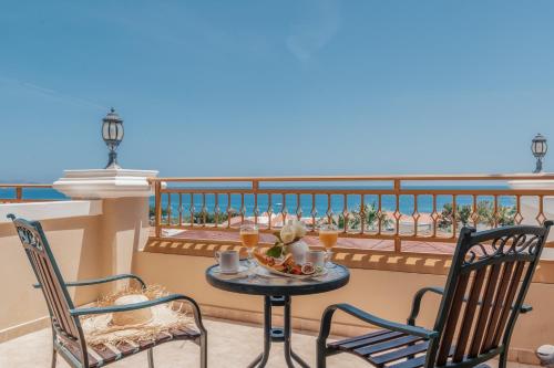 a table and chairs on a balcony with the ocean at Lindos Imperial Resort & Spa in Kiotari