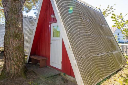 a red and white shed with a door next to a tree at Ostseecamping Peenemündung in Freest