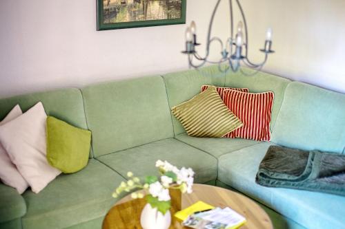 a green couch with pillows and a table at Ferienhaus Blütenzauber in Stennewitz