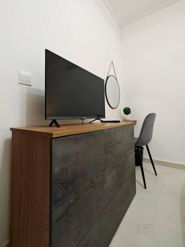 a television on top of a dresser with a chair at Blossom in Marsaskala