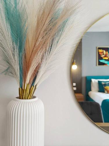a vase with feathers in front of a mirror at Blossom in Marsaskala