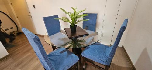 a glass table with blue chairs and a potted plant at Encantador Departamento excelente conectividad al centro y principales Rutas in Rancagua