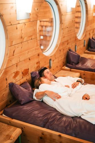 a man and a woman laying in bed in a cabin at Hotel Glemmtalerhof in Saalbach Hinterglemm