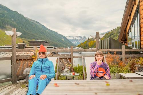 two children sitting on the deck of a house at Hotel Glemmtalerhof in Saalbach Hinterglemm