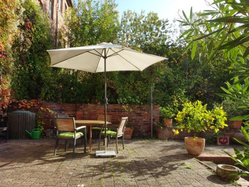 a table and chairs with an umbrella in a garden at Karl die Große Ferienwohnung in Dessau