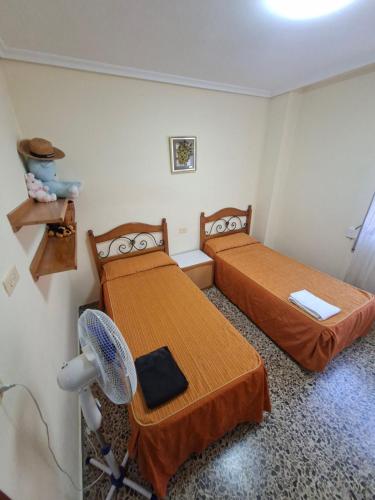 a room with two beds and a desk with a fan at APARTAMENTO BEATRIZ 2 in Burriana