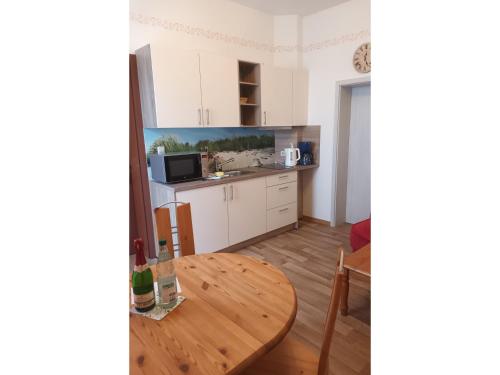 a kitchen with white cabinets and a wooden table at KOS - Haus Netti in Koserow