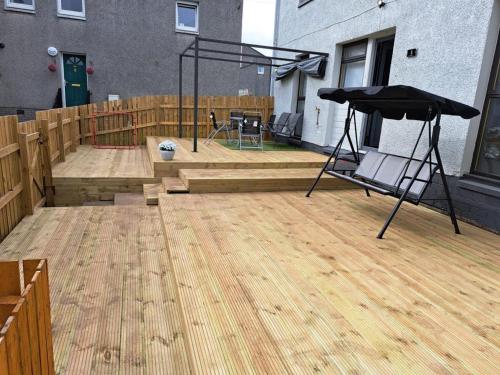 a large patio with a wooden deck with a swing at Newly renovated & furnished luxury bedroom in Kirkliston