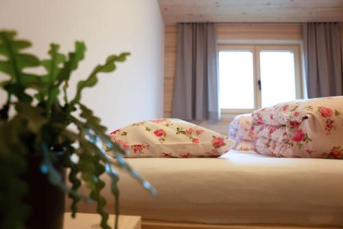 a bedroom with a bed with pillows and a window at Bregenzerwälder Appartements Familie Fink in Andelsbuch