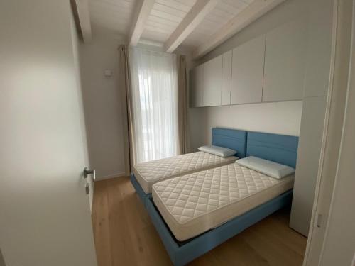 a small bedroom with a blue bed and a window at Wave Island in Lido di Jesolo