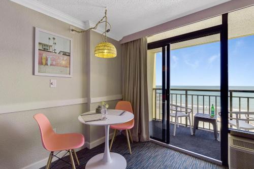 ein Esszimmer mit einem Tisch und Stühlen sowie einem Balkon in der Unterkunft Pink Surf by StayMareni - Oceanfront 2 Queens Suite in Myrtle Beach