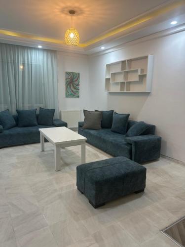 a living room with blue couches and a table at Coquette appart de plage in Hammam Sousse