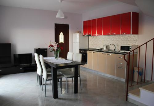 una cucina con tavolo, sedie e armadi rossi di Sun Gazing Villas a Drymon