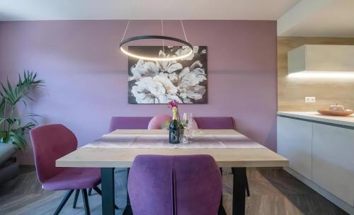 a dining room with a table and purple chairs at Gartenhof in Brixen
