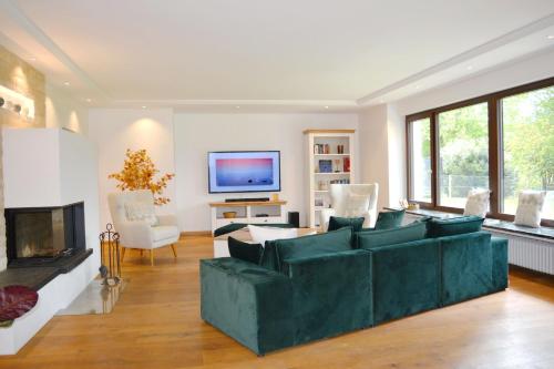 a living room with a green couch and a fireplace at ChiemseeZeit in Gstadt am Chiemsee