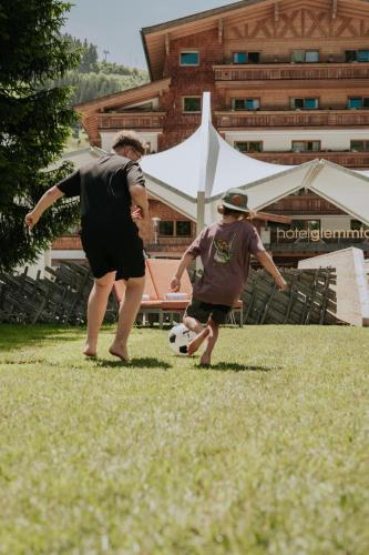 two men playing with a soccer ball in a field at Hotel Glemmtalerhof in Saalbach Hinterglemm