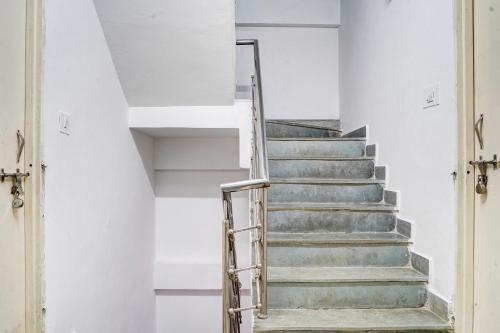 a staircase in a white room with a metal railing at Super Hotel O Neelbad Guest House in Bhopal