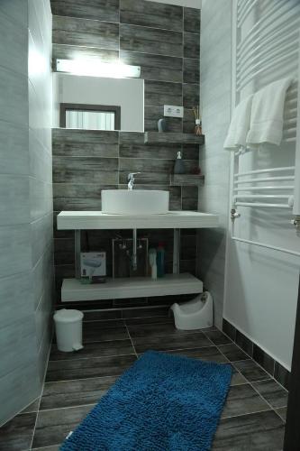 łazienka z umywalką i niebieskim dywanem w obiekcie Szofi Apartman w Hajduszoboszlo