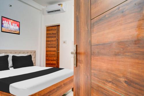 a bedroom with a bed and a wooden door at Super Hotel O Neelbad Guest House in Bhopal