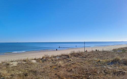 a beach with people walking on the sand and the ocean at Moderne Ferienwohnung "Parkblick" im Ostseebad Ückeritz in Ueckeritz