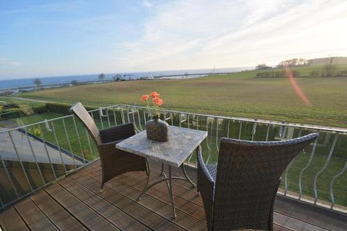 a table with chairs and a vase with flowers on a balcony at Hafenblick Whg 15 in Grömitz