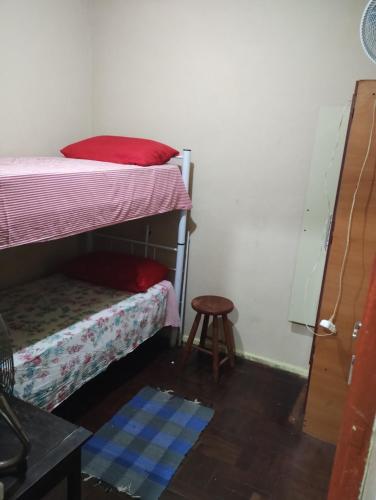 a bedroom with two bunk beds and a stool at Quartos individuais na saída do metrô estação Glória in Rio de Janeiro