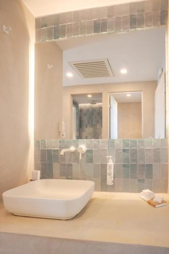 a large bathroom with a tub and a mirror at Apeiron Blue Santorini - Sustainable Adults Only 14 Plus in Fira