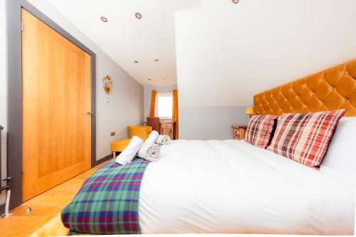 a bedroom with a large white bed with a wooden headboard at Luxury Seaview Cottage by Fairy Pools 2 in Carbost