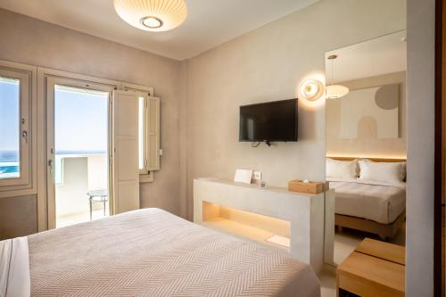 a bedroom with a bed and a tv on the wall at Apeiron Blue Santorini - Sustainable Adults Only 14 Plus in Fira