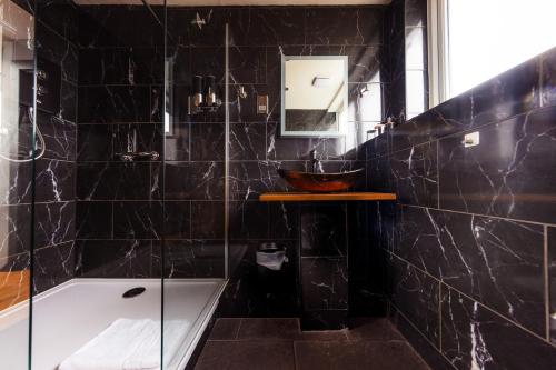 a black tiled bathroom with a sink and a shower at Luxury Seaview Cottage by Fairy Pools 2 in Carbost