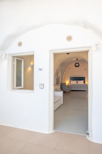 a white room with a door leading to a bedroom at Apeiron Blue Santorini - Sustainable Adults Only 14 Plus in Fira