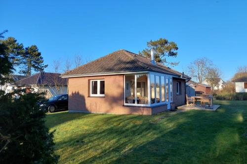 ein kleines Haus in einem Hof mit einer Wiese in der Unterkunft Deelswai 50, Bungalow in Goting