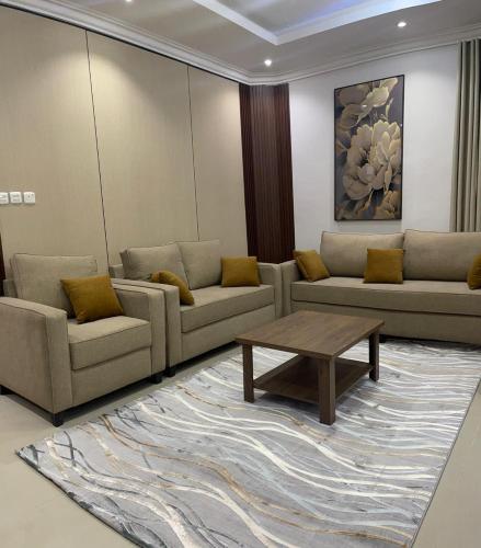 a living room with couches and a table on a rug at شقة ثلاثة غرف نوم وصالة in Al Baha