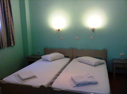 two beds in a room with two lights on the wall at Haritos Hotel - Geothermal Hot Swimming Pool in Mandrakion