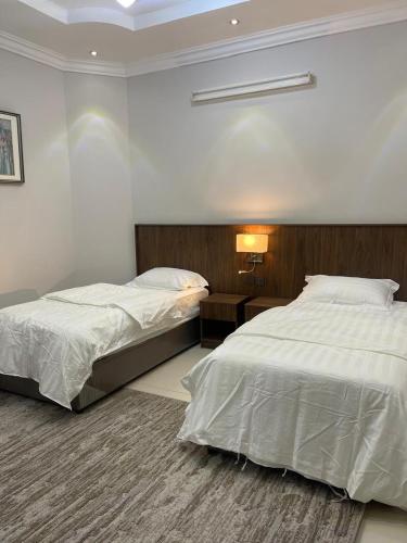 a bedroom with two beds and a lamp on a table at شقة ثلاثة غرف نوم وصالة 1 in Al Baha