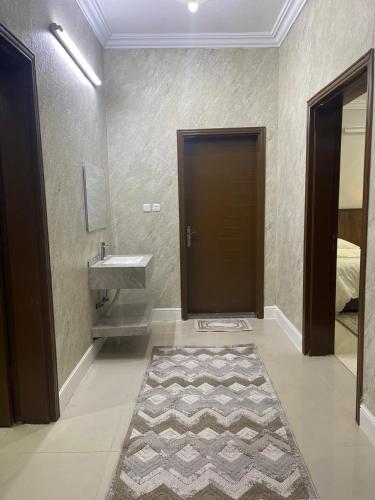 a bathroom with a sink and a door with a rug at شقة ثلاثة غرف نوم وصالة 1 in Al Baha