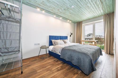 ein Schlafzimmer mit einem blauen Bett und einem Fenster in der Unterkunft Mano Malibu in Melnragė