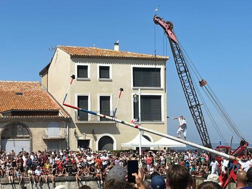 a crowd of people watching a man on a pole at Appartement standing vue étang de Thau in Marseillan