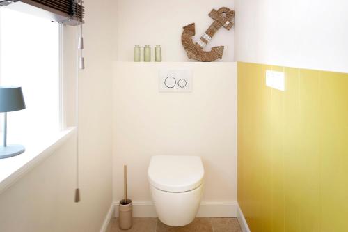 a bathroom with a toilet and a yellow wall at Marschkajüte in Oldsum