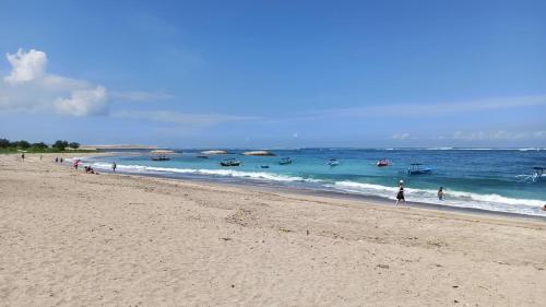 a group of people walking on a beach at ABI Hotel2 - 1 minute to the Beach and 1 second to the Mall in Ngurah Rai International Airport
