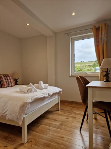 a bedroom with a bed and a desk and a window at Luxury Cottage by Fairy Pools 4 in Carbost