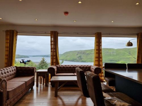 a living room with couches and a large window at Luxury Cottage by Fairy Pools 4 in Carbost